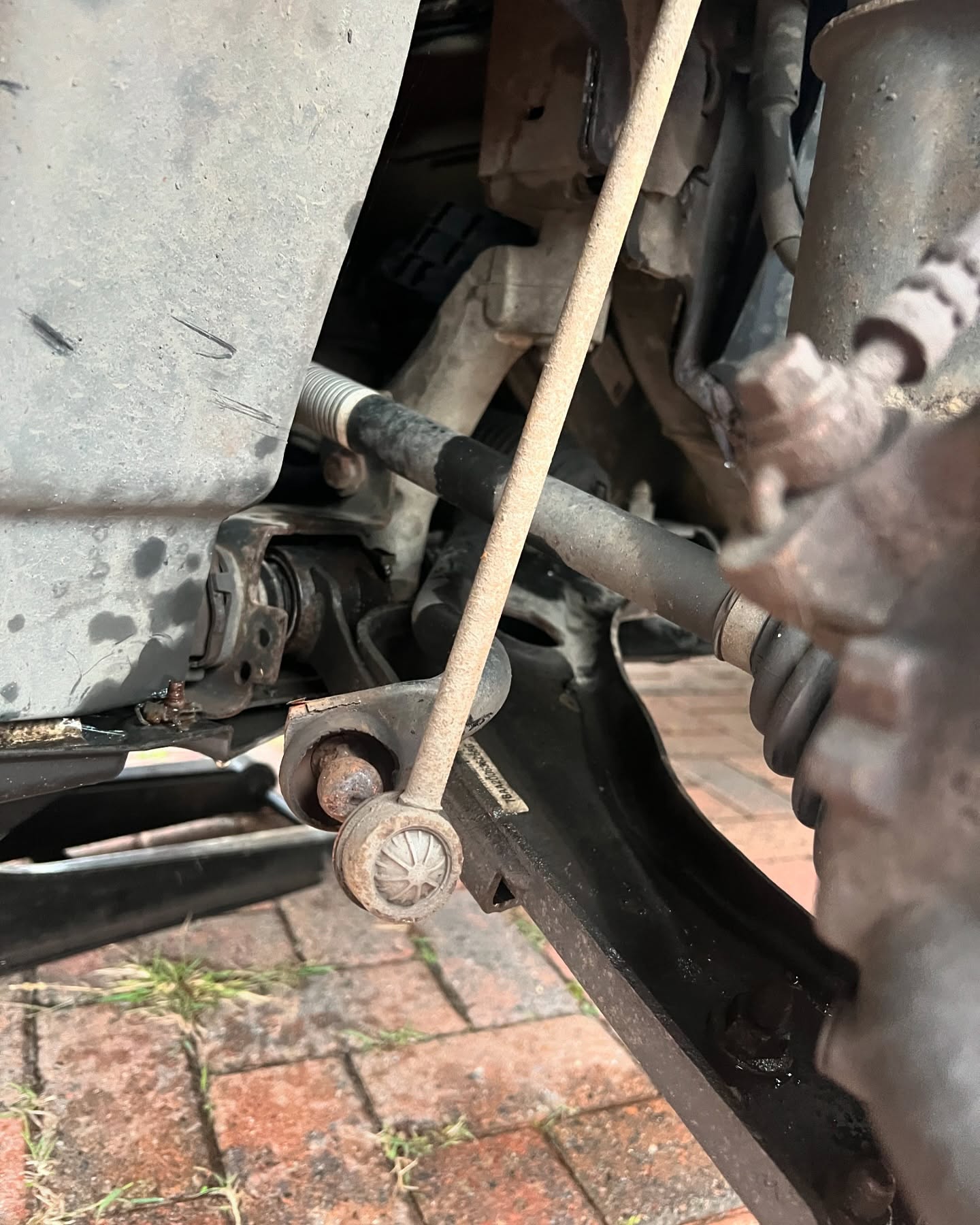 Worn suspension drop link inspected during a knocking-noise repair